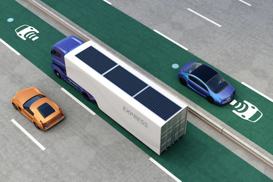 Rendering of truck and cars driving on green electric vehicle charging roadway lane.